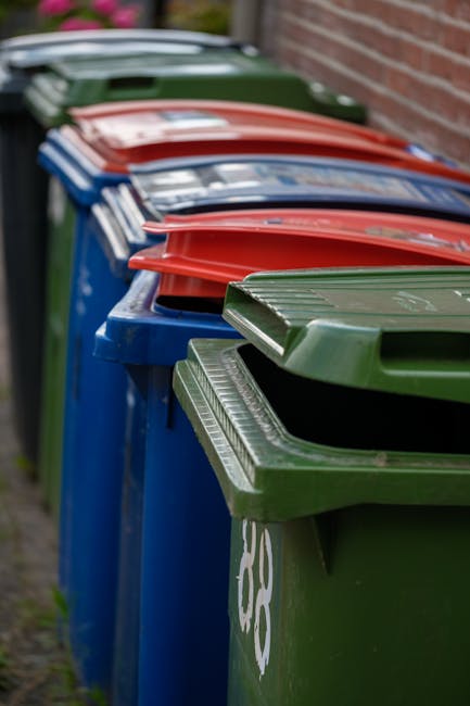 A close-up view of two black plastic rubbish bags tightly tied at the top, with one bag positioned slightly in front of the other. The bags have a shiny, crinkled surface, characteristic of standard r
